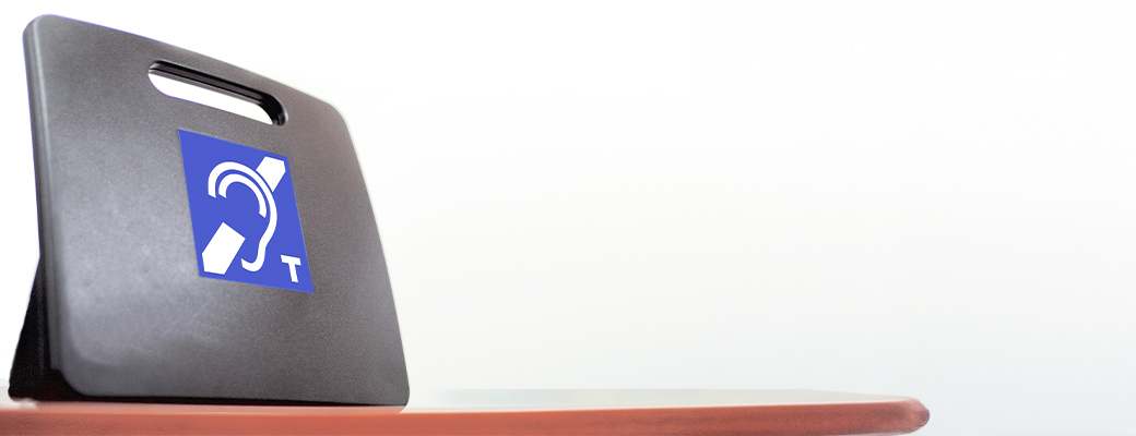 Image of telecoil logo on a stand that is resting on a table surface